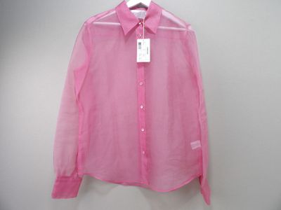 une chemise rose suspendue à un cintre sur un mur blanc