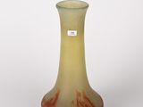un vase jaune et rouge posé sur une surface blanche