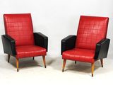 une paire de fauteuils en cuir rouge et noir posés contre un mur blanc