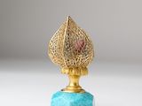an image of a gold vase with a blue base on a white surface