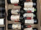Plusieurs bouteilles de vin se trouvent dans un carton posé sur un sol carrelé.