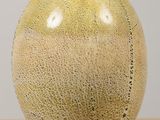 un vase jaune muni d'une anse, posé sur une table en bois