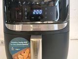 an air fryer sitting on a counter with a digital clock on it