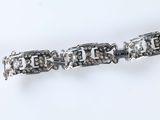 a close up of a silver bracelet with diamonds on a white surface