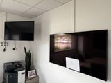 un téléviseur à écran plat fixé au mur au-dessus d'une imprimante
