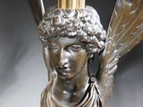 a statue of a woman with wings on top of a lamp