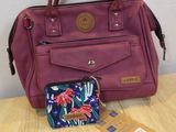 purple handbag and wallet sitting on a wooden table next to a white wall
