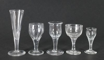 cinq verres à vin et un vase posés sur une table