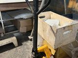 a fork truck with a box on it in front of a pile of boxes