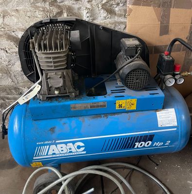 a blue air compressor sitting on the ground next to a box