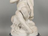 une statue représentant un garçon tenant un oiseau, posée sur un socle