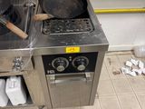 une cuisinière sur laquelle est posée une poêle, dans une cuisine