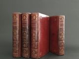 three red books are stacked on top of each other on a gray surface