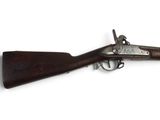 un vieux fusil exposé sur une surface blanche