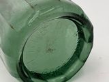 a green glass bottle sitting on a white surface