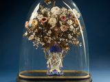 un vase de fleurs sous une cloche en verre, posé sur un fond bleu