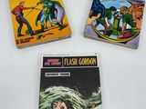 three vintage flash gordon comics on display in a display case