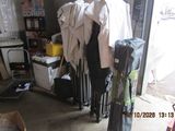 an image of a messy garage with clothes on a rack