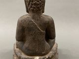 statue of a person sitting in a meditation position on a gray surface