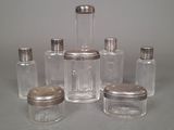 six clear glass jars with silver lids on a gray surface