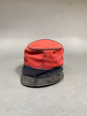 un chapeau rouge et noir posé sur une surface grise
