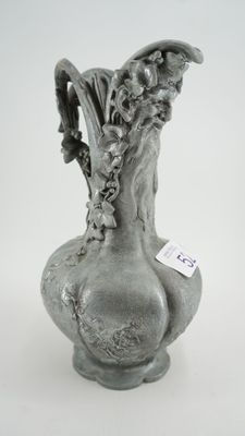 un vase gris contenant des fleurs, posé sur une surface blanche