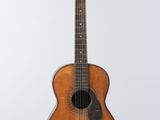 an old wooden guitar hanging from a string on a white wall