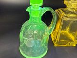 des flacons de parfum en verre jaune et vert posés sur une surface noire