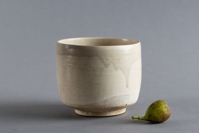 un petit bol blanc avec une poire posée à côté