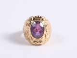 a close up of a gold ring with a purple stone