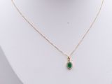 a gold necklace with a green stone pendant on a mannequin