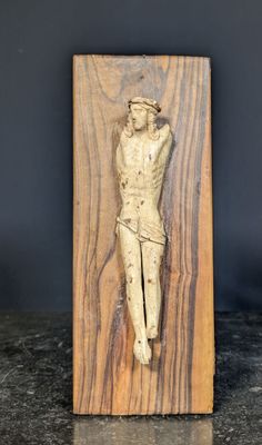 sculpture représentant un homme sur une croix, sur une plaque en bois