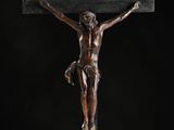 a bronze statue of jesus on the cross on a black background