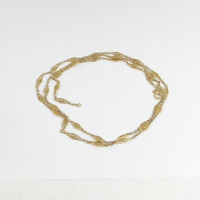 un collier en or dont la chaîne est posée sur une surface blanche