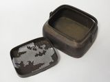 a small metal container with a cross - stitch design on it