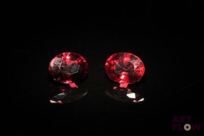 une paire de boucles d'oreilles à clous en verre rouge et noir posées sur un fond noir