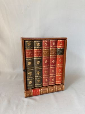 trois livres dans un coffret en bois posé sur une surface blanche