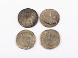 four coins of different sizes and shapes on a white surface
