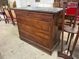 a wooden dresser with a marble top in a room