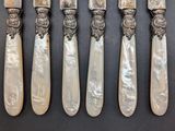 four silverware pieces with mother of pearl in them on a black surface