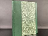 an old book with a green cover sitting on top of a table