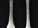 three forks are sitting next to each other on a black surface