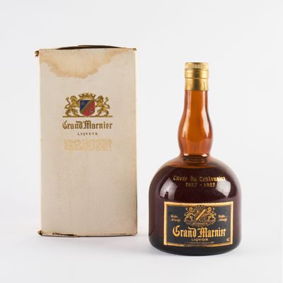 une vieille bouteille de Grand Marnier posée à côté d'une boîte en carton