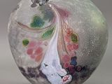 a glass vase with a painting on it sitting on a table