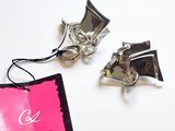 une étiquette rose ornée d'un nœud argenté, posée à côté d'une paire de chaussures