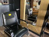 a black leather chair in front of a mirror in a barber shop