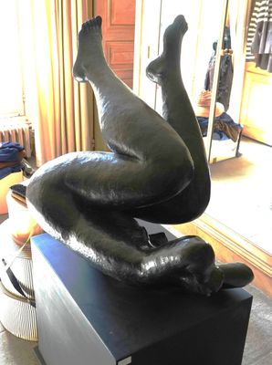 une statue représentant une personne allongée sur une caisse dans un salon