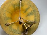 a bell hanging from the side of a yellow bowl