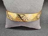 une photo en gros plan d'un bracelet en or posé sur un oreiller