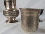 two silver cups and a silver pitcher on a white background